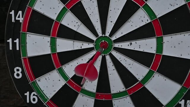 Red dart hitting bullseye on dartboard, close-up target game and precision throw