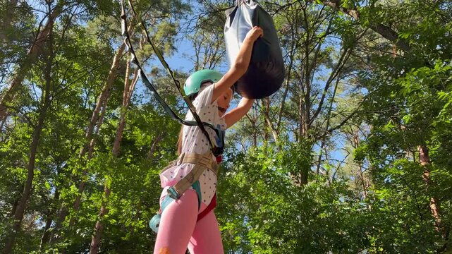 A primary school-aged girl navigates an obstacle course at a rope course. An active outdoor recreational challenge.