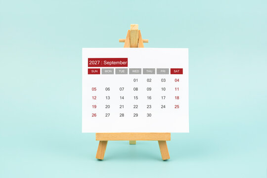Calendar page for September 2027 with wood easel on a blue background.