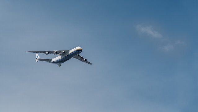 KYIV, UKRAINE - AUGUST 19, 2021: Wide view of Antonov An-225 Mriya, the world's largest cargo airplane, flying in clear blue sky with copy space.