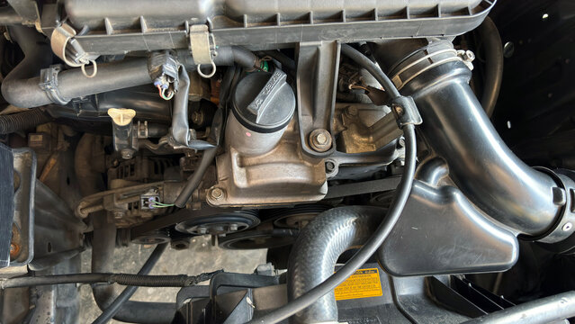 Close-up of underside car engine showing metallic pipes, hoses, and mechanical components. Perfect for automotive diagnostics, repair, and mechanical inspection.