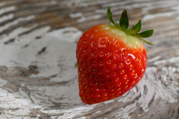 Fresh strawberry resting on a rustic wooden surface inviting taste and freshness © Михаил Шорохов