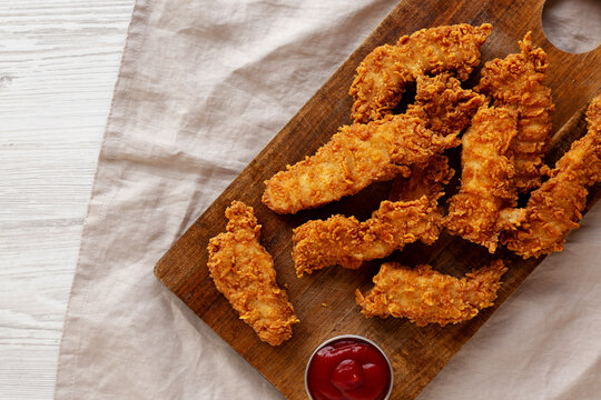 Organic Crispy Chicken Strips with Ketchup on a Wooden Board, top view. Copy space.