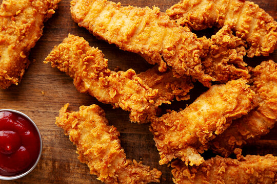 Organic Crispy Chicken Strips with Ketchup on a Wooden Board, top view. Close-up.
