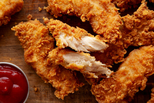 Organic Crispy Chicken Strips with Ketchup on a Wooden Board, top view. Close-up.