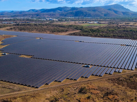 Aerial view of the Sun Metals Corporation solar farm in Stuart, featuring rows of photovoltaic panels set against a backdrop of hills and dry landscape. Stuart, Queensland, Australia.