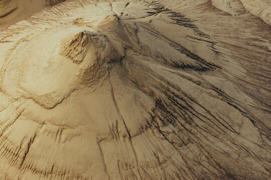 Aerial view of sand piles in the warm sun with textured erosion patterns and golden light in Poland.