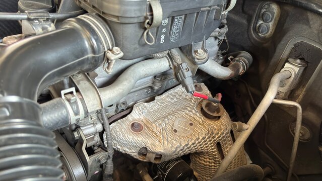  Detailed view of automobile engine compartment showing intake manifold, black tubing, metallic parts, and hoses. Represents automotive maintenance, diagnostics, and mechanical engineering.