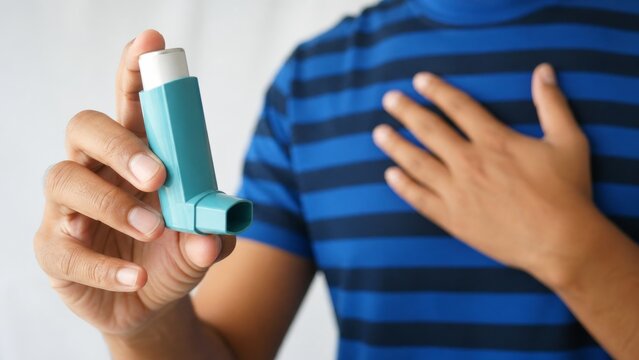 Person using asthma inhaler while holding chest for breathing relief