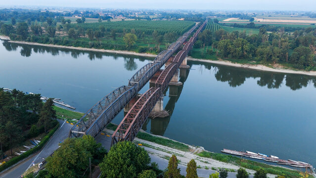 Aerial view of the railway bridge over the Po River with low water levels during a summer heatwave at sunrise in Cremona, Lombardy, Italy.