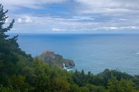 serene coastal scene with lighthouse on rocky coastline under high angle sky view in travel and nature setting with blue and green colors and wood, rock, metal materials.