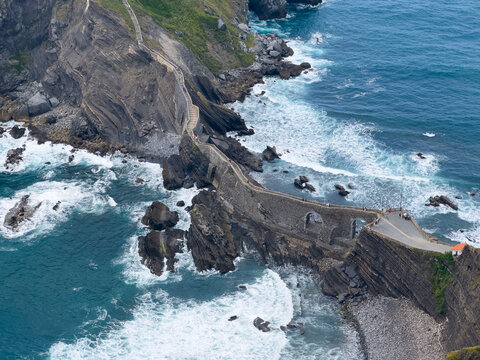 winding pathway along cliff edge with rock formations and ocean waves in serene coastal cliffs, aerial perspective, adventure and tranquility, blue and green tones, stone and concrete, safe.
