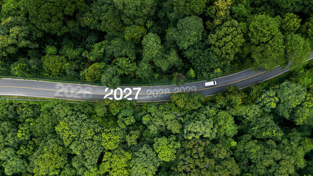 Aerial view of lush green forest with 2027 text on the road, concept for new year 2027, business goals, ESG sustainability, and growth strategy.