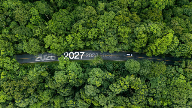 Aerial view of lush green forest with 2027 text on the road, concept for new year 2027, business goals, ESG sustainability, and growth strategy.