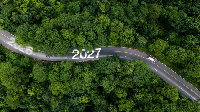 Aerial view of lush green forest with 2027 text on the road, concept for new year 2027, business goals, ESG sustainability, and growth strategy.