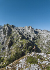 Fototapeta premium Hiker Standing on Rocky Summit Overlooking Valley
