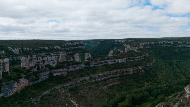 serene canyon landscape with rock formations and lush vegetation in an outdoor natural setting viewed from an aerial perspective, Risco los camellos, Cascada de Orbaneja del Castillo