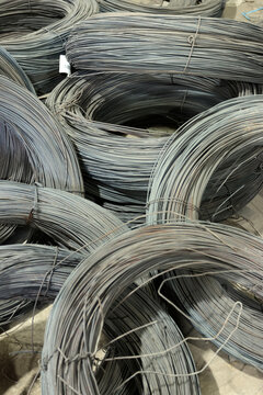 Close-up of coiled steel wire bundles stacked on the floor inside an industrial metal warehouse.