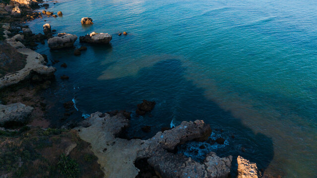 serene rocky coastline with waves crashing against cliffs, aerial perspective of natural beauty in travel photography, nature landscape with blue and brown tones. Praia dos Aveiros Portugal