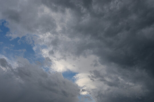 Dramatic gloomy sky densely covered with dark storm clouds with small patches of blue sky breaking 