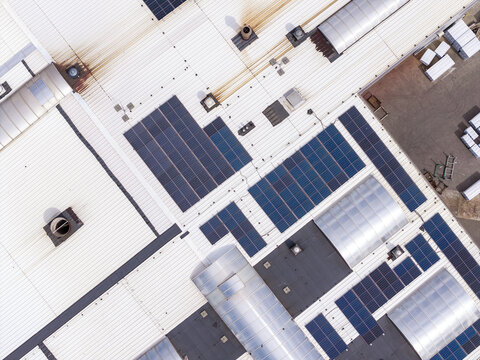 Aerial view of a tissue paper reels production facility featuring solar panels on the roof and stacks of materials in the yard in Poland.