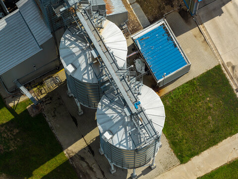 Aerial view of production scale storage silo system with metal tanks and conveyor bridge in Poland.