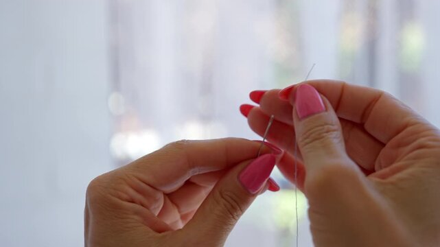 Woman's hands carefully threading a needle
