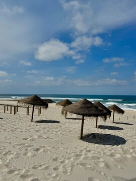 Traditional straw parasols on a sandy beach by the Atlantic Ocean in Costa Nova, Portugal