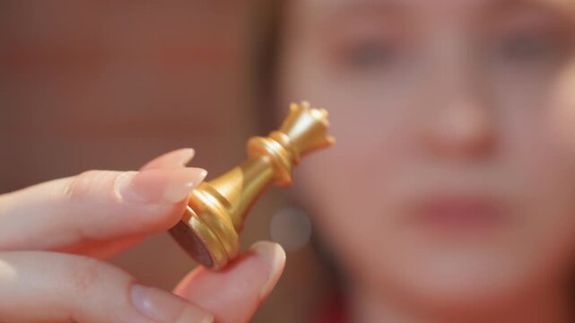 Closeup caucasian woman showing queen piece in brick cafe, confident contender with subtle smile, steady fingers, coffee cup offframe, warm tones, competitive mood, gaze fixed on board.