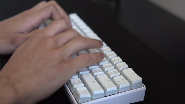 Close-up selective focus of a person typing on a modern white computer keyboard.