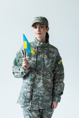 Fototapeta premium Young beautiful woman proudly holding Ukraine flag in military uniform on Independence Day