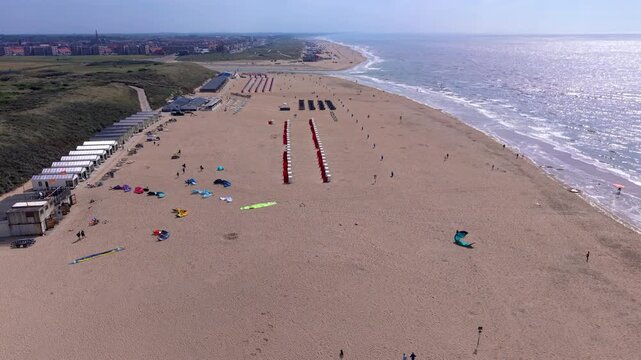 Aerial view video clip of Katwijk aan Zee wide sandy beach, kitesurfing equipment, beach cabins, coastal dunes, and North Sea shore in South Holland, Netherlands on a sunny day