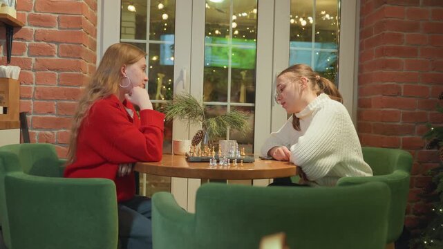Friends pause game at cafe table, one player offers supportive gesture while opponent rests head, steaming coffee cups and small plates, exposed brick and warm string lights, tense decision moment
