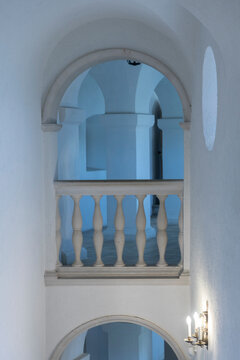 Decorative arched window and balustrade on the facade of a historic building. Architectural detail with white walls and blue glass.