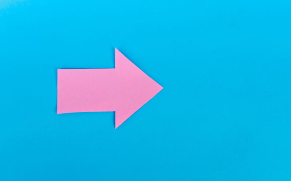 Single pink paper arrow pointing right on blue background
