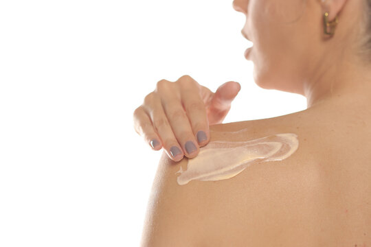 Description:
Rear view close-up of a woman spreading lotion on her bare shoulder, body care routine, on white background.