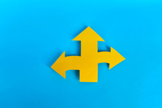 Yellow three direction paper arrow representing multiple choices and paths on blue background
