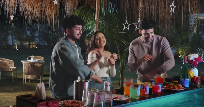 Indian young adult gen z relax male female group dancing on music sing song have fun joy at picnic trip Happy girl boy man woman standing around bar table spend good time enjoy night decor party place