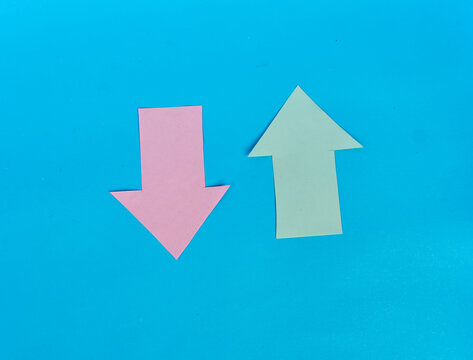 Pink downward arrow and green upward arrow showing opposite directions on blue background
