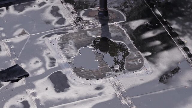 Rain and water damage across industrial commercial business rooftop and flat roof on rubber sealed roofing causing leaks, rainfall tears, and leaking into building exterior from above drone aerial 4k
