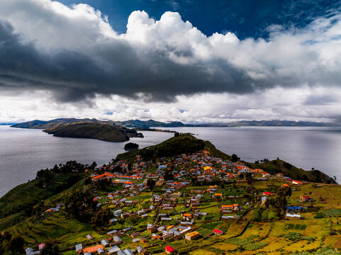 Aerial view of Isla del Sol with its traditional village, terraced fields, and stone walls surrounded by the vast waters of Lake Titicaca, Bolivia.