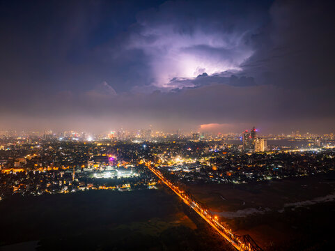 Aerial view of Long Bien Bridge illuminated at night with a dramatic lightning storm over the city skyline in Hong Ha, Hanoi, Vietnam.