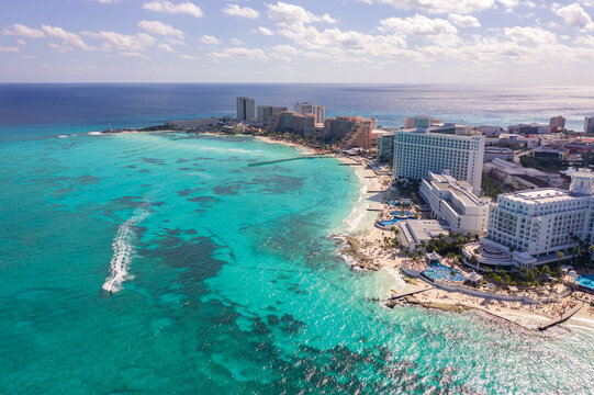 Aerial view of the Hotel Zone in Cancun with turquoise Caribbean waters, white sandy beaches, luxury resorts, and a jet ski leaving a wake in the sea, Cancun, Quintana Roo, Mexico.