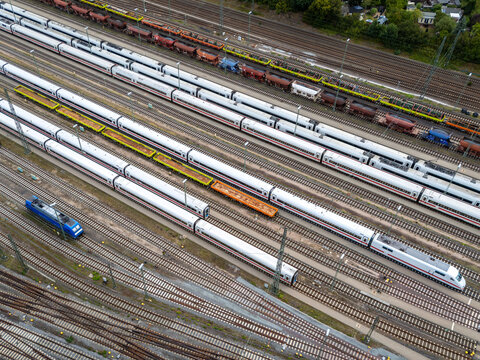 Aerial view of multiple passenger trains and freight cars parked on parallel tracks at a railway depot in Germany.