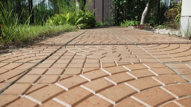 Macro pavement pattern with dramatic perspective, lowangle closeup of circular paver design with crisp contrast between sunlit ridges and shadowed grooves, gritty sand in seams, grass border and worn