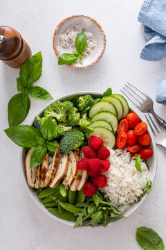 Healthy lunch bowl with grilled chicken, fresh vegetables and raspberries