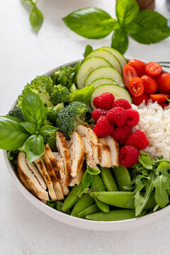 Healthy lunch bowl with grilled chicken, fresh vegetables and raspberries