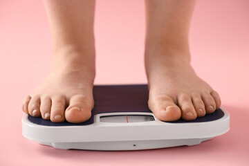 Fototapeta premium Overweight woman on scale against pink background, closeup