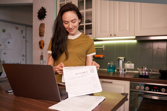 Woman reviewing utility bills in a modern kitchen