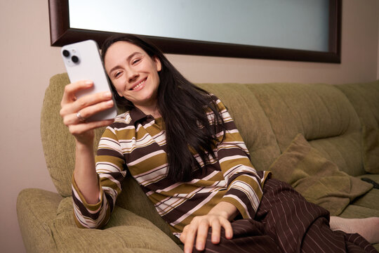 Woman smiles while looking at her phone on a couch